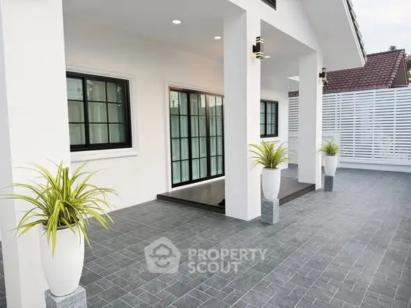 Modern exterior with sleek design, large windows, and stylish potted plants on a spacious tiled patio.