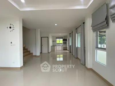 Spacious open-plan living area with modern kitchen and large windows in a bright, airy home.