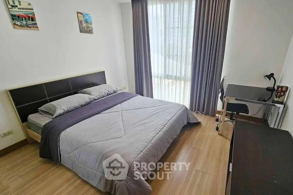 Modern bedroom with cozy bed, study desk, and large window with curtains in a stylish apartment.