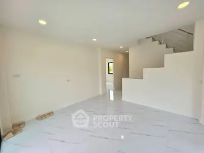 Spacious modern living room with sleek white tiles and staircase, perfect for contemporary living.