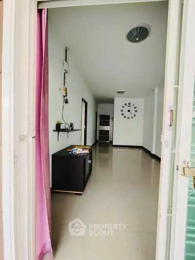Spacious unfurnished room with modern wall clock and sleek tile flooring, ideal for customization.