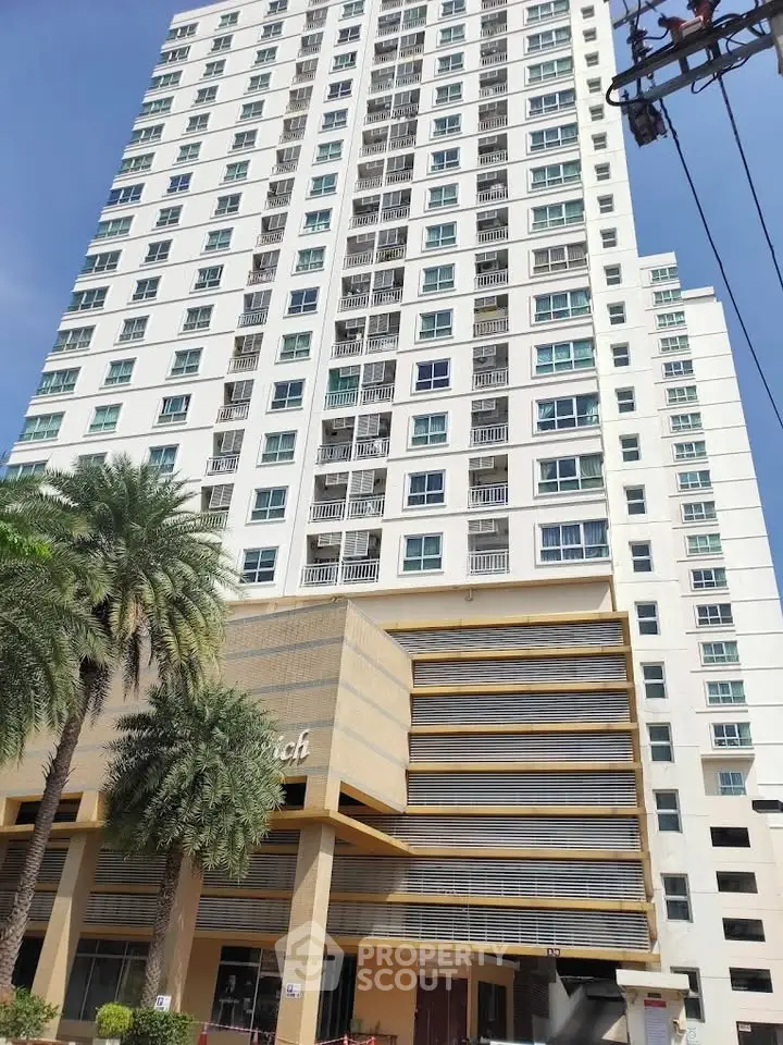 Modern high-rise building with palm trees and clear blue sky, showcasing urban living.