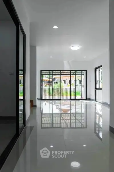 Spacious modern living room with large windows and glossy floors