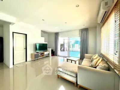 Spacious living room with modern decor and large windows offering abundant natural light.