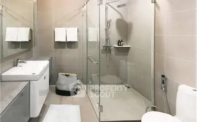 Modern bathroom with glass shower and sleek fixtures in contemporary apartment.