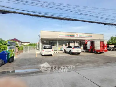 Modern convenience store exterior with parking area and vehicles in front, showcasing a clean and accessible location.