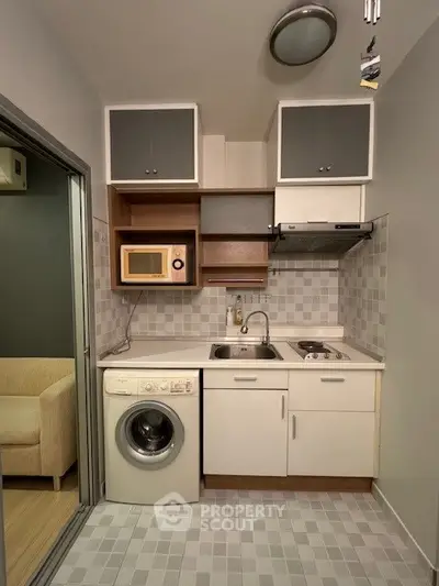 Compact modern kitchen with washing machine and microwave in cozy apartment