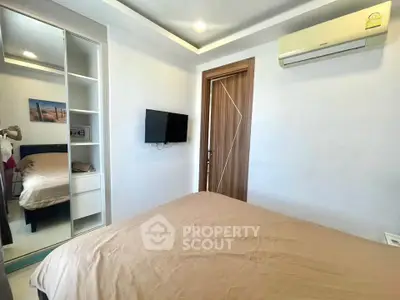 Cozy bedroom with modern decor, featuring a wall-mounted TV and air conditioning for comfort.