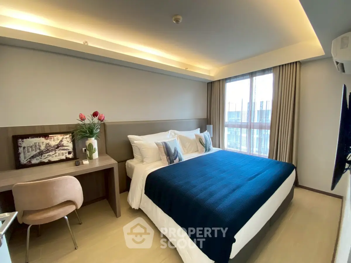 Modern bedroom with stylish decor and large window offering natural light