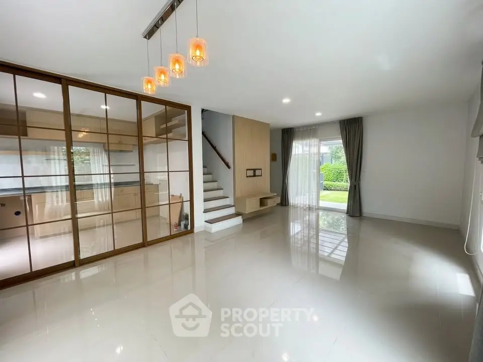 Spacious modern living room with glass doors and garden view, perfect for family gatherings.