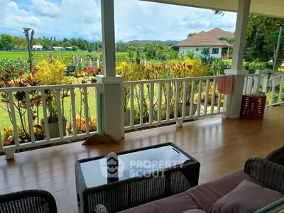 Charming balcony with lush garden view and cozy seating area.