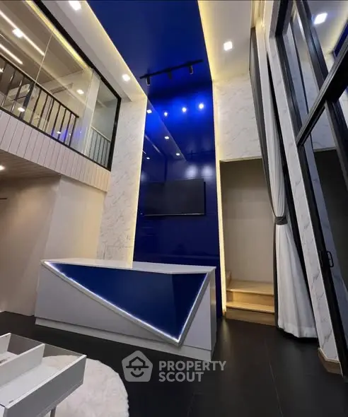 Modern duplex living room with high ceilings and sleek blue accents