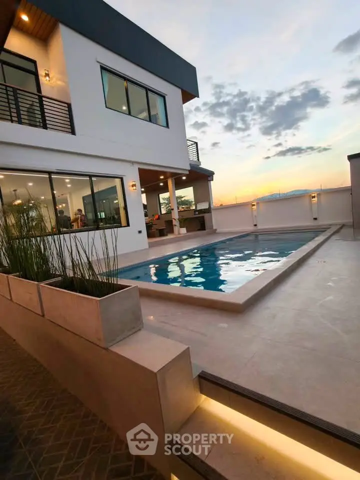 Luxurious modern home with stunning pool and sunset view, perfect for relaxation and entertainment.