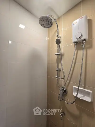 Modern bathroom shower with sleek fixtures and water heater in a stylish tiled setting.