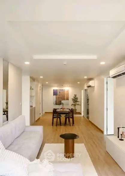 Spacious modern living room with elegant decor and dining area, featuring sleek air conditioning units.