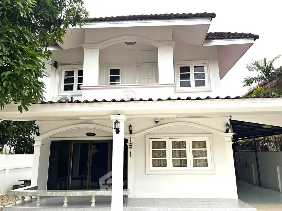 Charming two-story white house with elegant columns and lush greenery