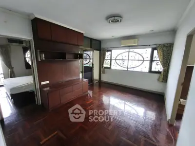 Spacious living room with wooden flooring and large windows in a modern apartment.