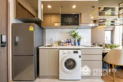 Modern kitchen with sleek cabinets, washing machine, and dining area in stylish apartment.