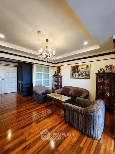 Elegant living room with hardwood floors, chandelier, and cozy seating area.