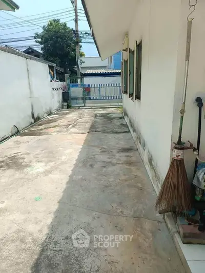 Spacious outdoor area with concrete flooring and gated entrance, ideal for parking or outdoor activities.