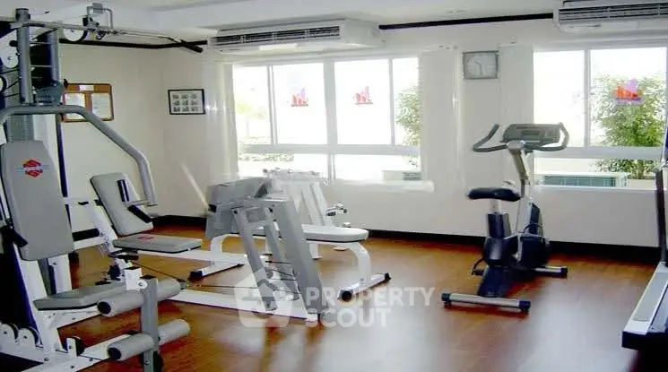 Spacious gym with modern equipment and large windows for natural light.
