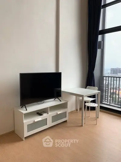 Modern living room with TV and dining area, featuring large windows and city view.