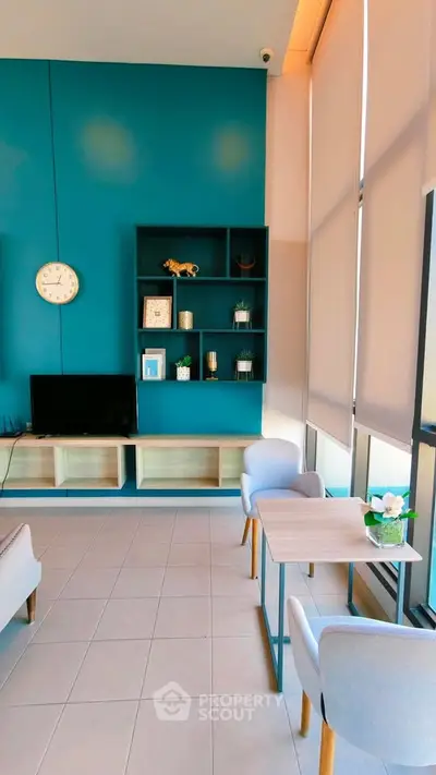 Modern living room with teal accent wall, stylish shelving, and cozy seating area.