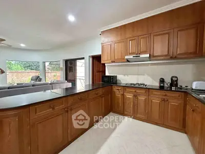 Spacious kitchen with wooden cabinets and modern appliances, open layout to living area.