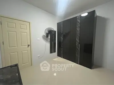 Modern bedroom with sleek black wardrobe and wall-mounted fan