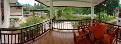Charming balcony with wooden furniture and lush garden view, perfect for relaxation and outdoor dining.