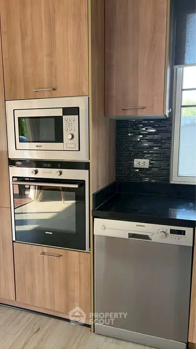 Modern kitchen with built-in oven and microwave, sleek cabinetry, and dishwasher