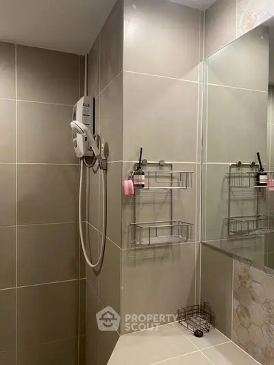 Modern bathroom with sleek tiles and wall-mounted shower in contemporary apartment.