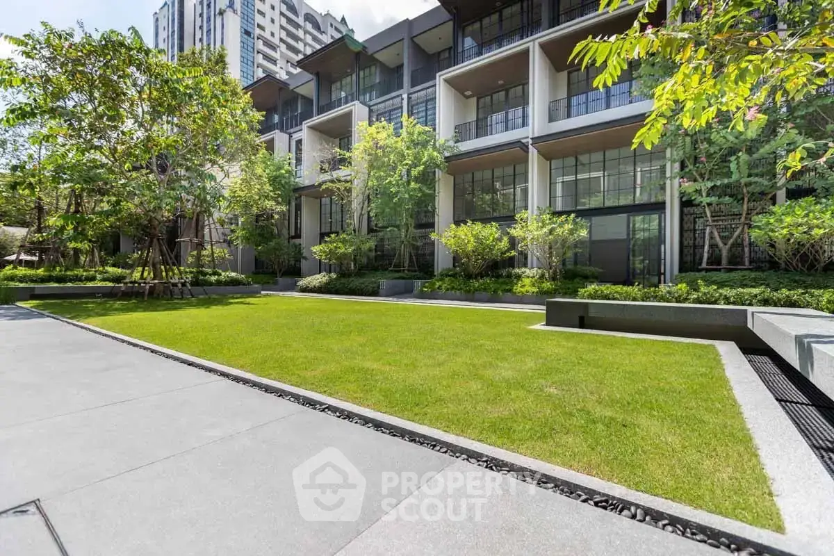Modern residential building with lush green garden and spacious outdoor area.