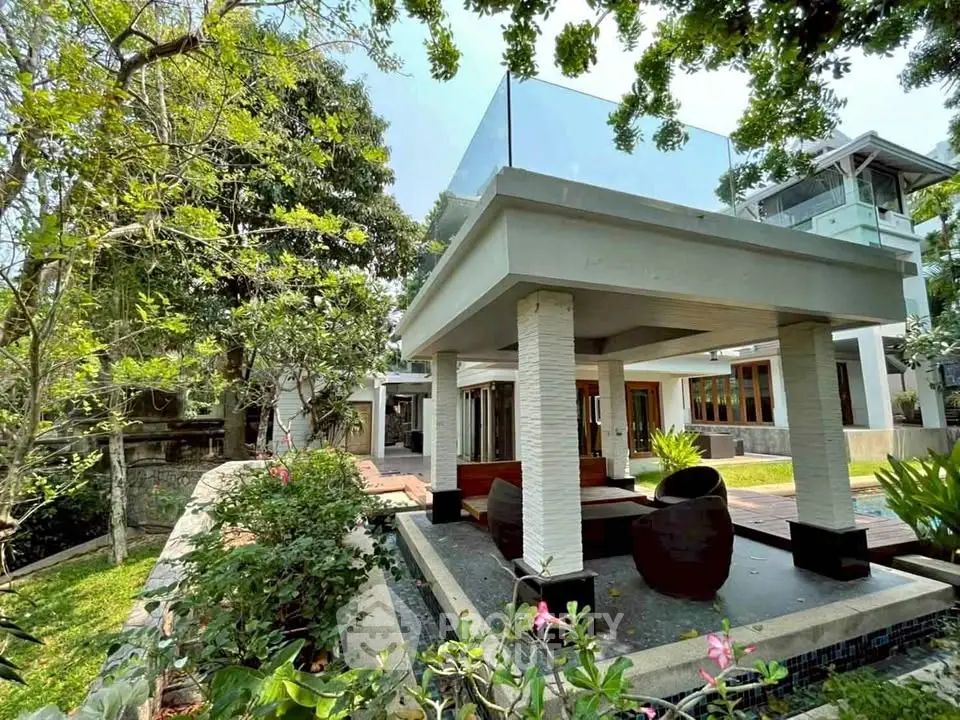 Luxurious modern villa with lush garden and spacious outdoor seating area, perfect for relaxation and entertaining.