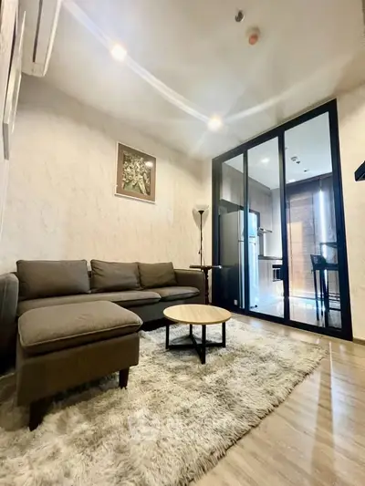 Modern living room with cozy sofa, stylish decor, and open layout leading to kitchen area.