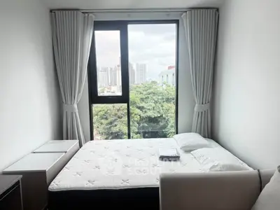 Bright bedroom with large window offering city and greenery views, featuring a comfortable bed and modern decor.