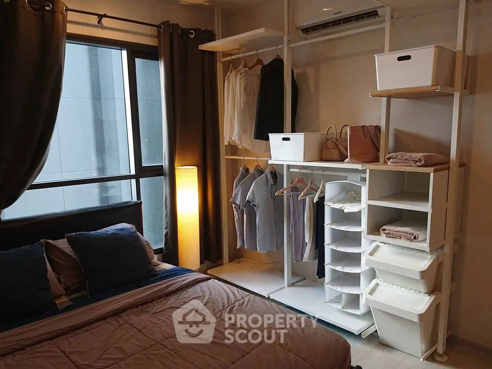 Cozy bedroom with modern open closet and large window for natural light.