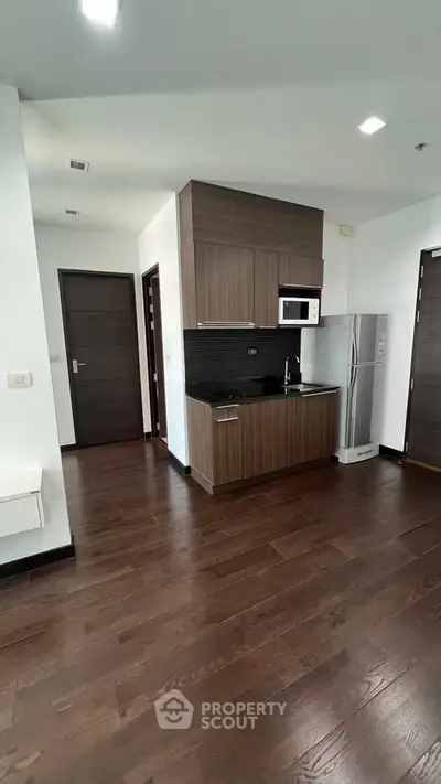 Modern kitchen with sleek wooden cabinetry and stainless steel appliances in a stylish apartment.