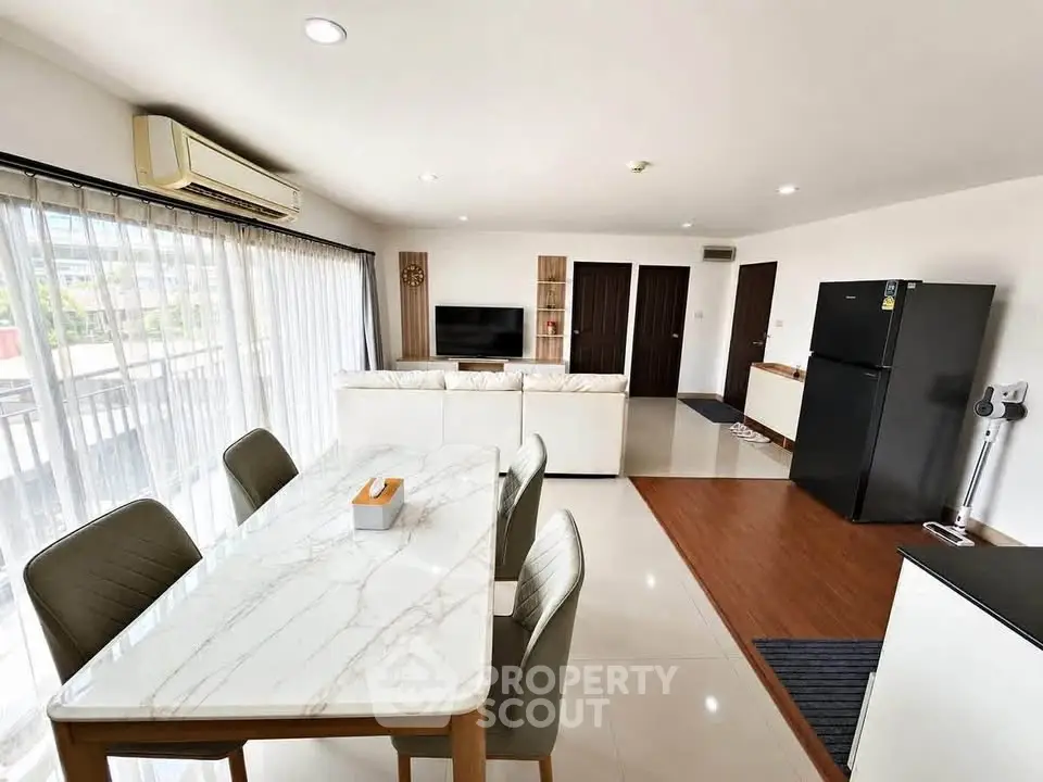 Spacious modern living room with dining area and sleek kitchen in open layout apartment.