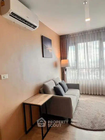 Cozy living room with modern sofa and air conditioning, featuring large window with city view.