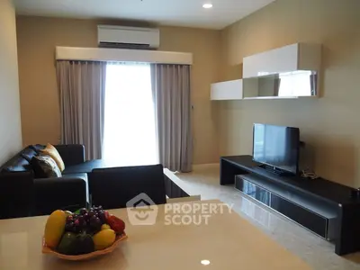 Modern living room with sleek furniture and natural light, featuring a stylish TV setup and cozy seating area.