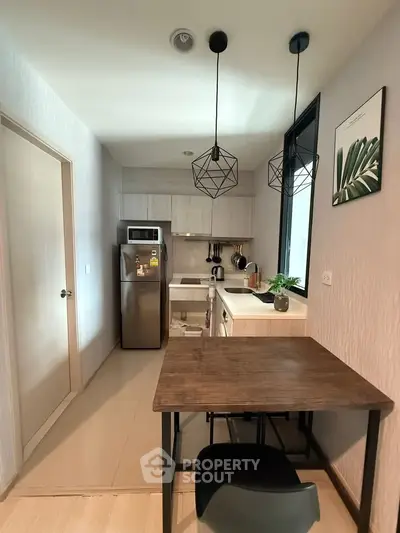 Modern kitchen with sleek design, featuring stainless steel appliances and stylish pendant lighting.