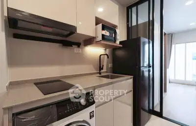Modern kitchen with sleek appliances and washer in compact open layout