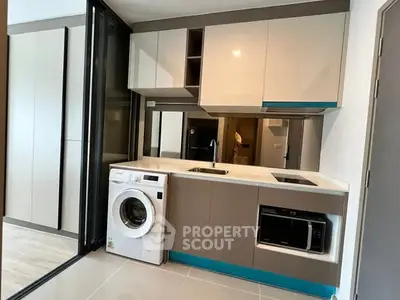 Modern compact kitchen with washing machine and microwave in sleek apartment