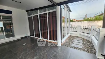 Spacious modern patio with glass doors and stone pathway, perfect for relaxation.