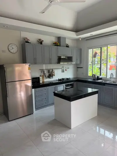 Modern kitchen with sleek cabinetry and island, featuring stainless steel appliances and a gas stove.