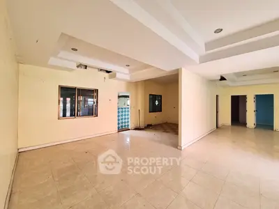 Spacious empty living room with tiled flooring and recessed lighting, ready for customization.