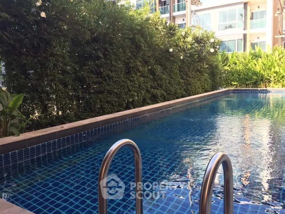 Luxurious residential pool surrounded by lush greenery and modern apartments, perfect for relaxation and leisure.