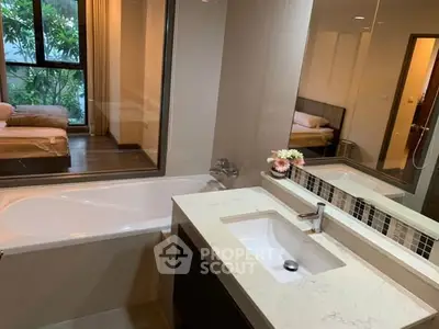 Modern bathroom with bathtub and view into cozy bedroom