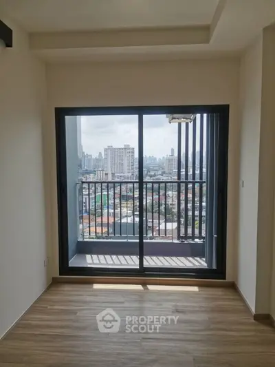 Spacious and bright room with large windows leading to a balcony offering a panoramic city view, perfect for urban living.